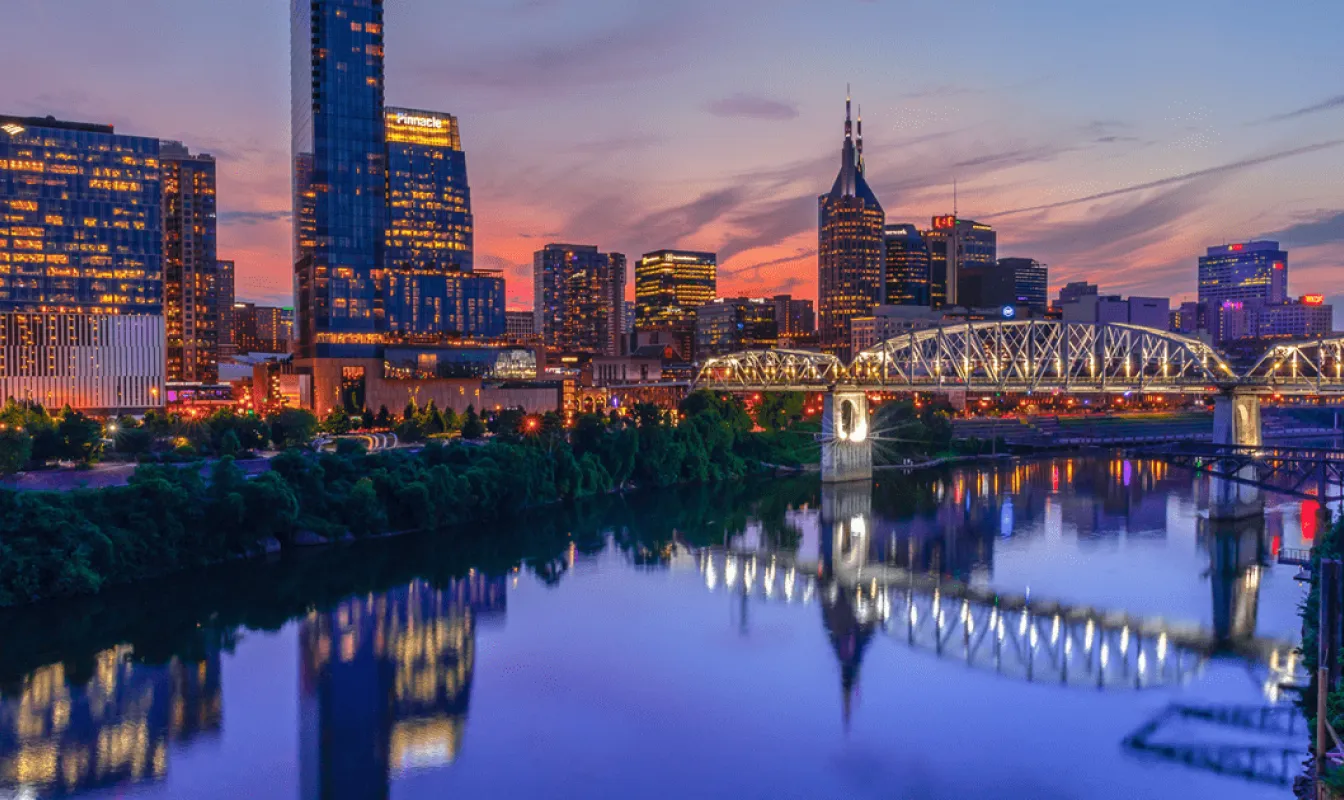 The Nashville skyline and Cumberland River lit up at dusk