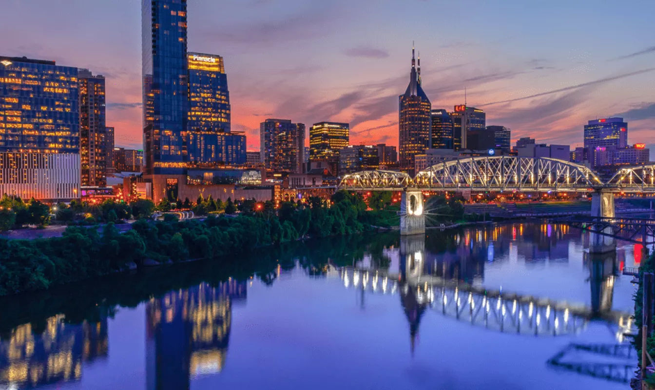 The Nashville skyline and Cumberland River lit up at dusk