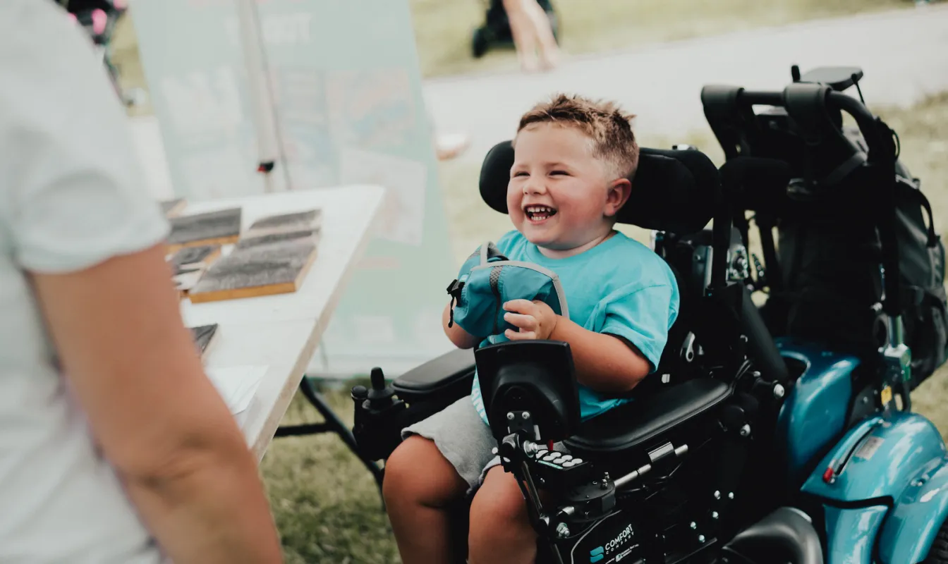 Picture of a smiling child using a wheelchair
