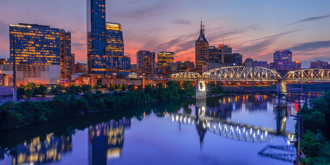 The Nashville skyline and Cumberland River lit up at dusk