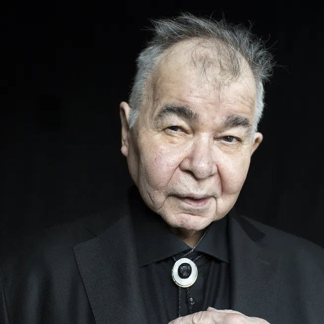 Portrait of John Prine in a black suit