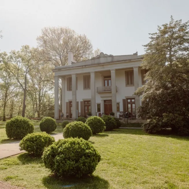 The Mansion, C. 1853, is a greek revival mansion featuring limestone columns and is accessible through a guided tour for public and private tours.
