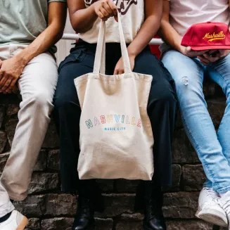 People sitting with a Nashville tote bag and souvenir hat
