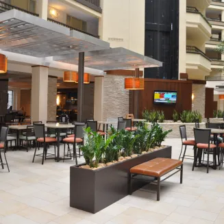 Hotel atrium dining area with tables, chairs, and modern decor.