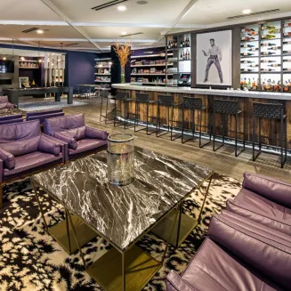 Hotel bar with modern seating, marble tables, and wall display of spirits