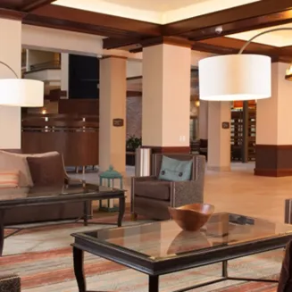 Embassy Suites airport lobby with lounge seating, glass coffee tables, and large drum pendant lights.