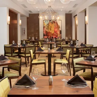 Two Rivers Café dining room with wood tables, lime-green chairs, black napkins, and globe pendant lights.