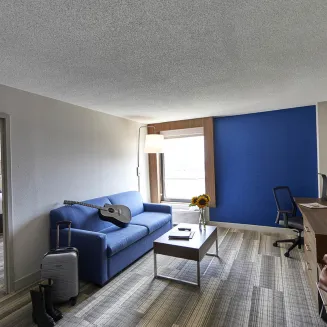 Hotel suite with living area, sofa, desk, and adjoining bedroom