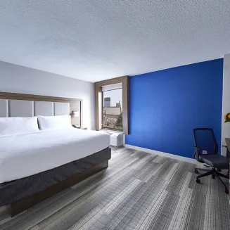 Hotel guest room with king bed, desk, and blue accent wall