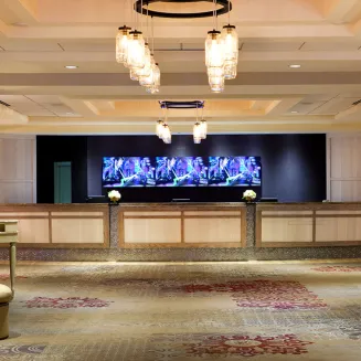 Hotel lobby reception area with illuminated front desk and elegant lighting fixtures.
