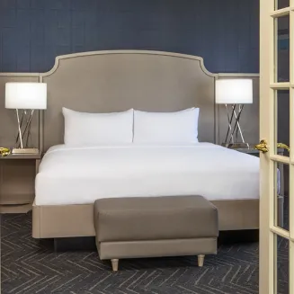 Hotel suite bedroom with king bed viewed through French doors.