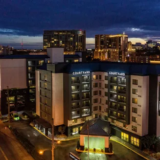 Courtyard by Marriott hotel exterior at night with city lights in the background.