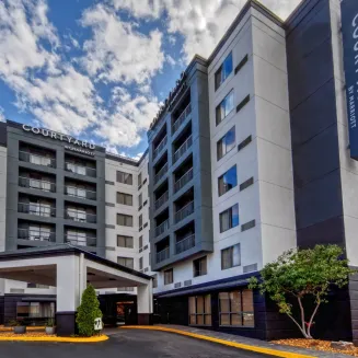 Exterior of Courtyard by Marriott hotel with entrance and multiple stories under a blue sky.