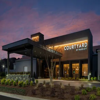 Exterior of Courtyard by Marriott hotel at dusk with illuminated entrance.