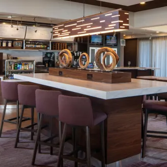 Hotel bistro with modern lighting, high-top tables, and seating area.