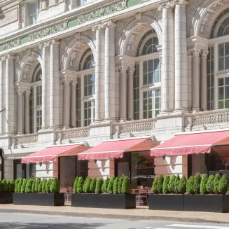Historic building façade with arched windows, pink awnings, and sidewalk patio seating. Nashville, TN.