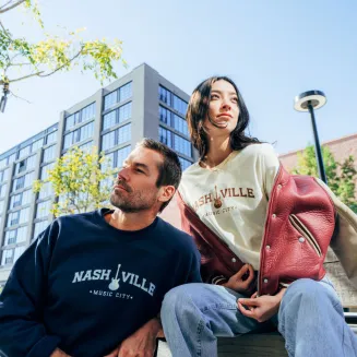 Two people wearing Nashville sweatshirts outdoors