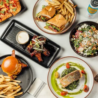 Enjoy craveable apps and pub favorites served alongside expertly prepared entrées, plus a fully stocked bar featuring signature cocktails and craft beer, Picture here are our Tennessee Whiskey Glazed BBQ Wings, Hipster Flatbread, Steak Sandwich, Kale & Apple Salad, Smashville Burger, and Crispy Salmon.