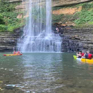 Two groups of kayakers float in a calm pool beneath Fancher Falls.