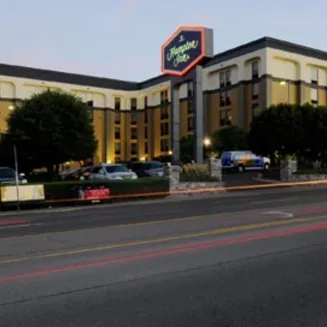 Exterior of Hampton Inn hotel at dusk with parking area and street view.
