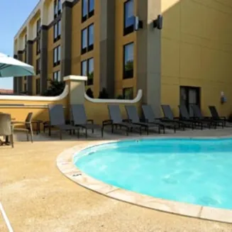 Outdoor hotel pool with lounge chairs and umbrella seating area.