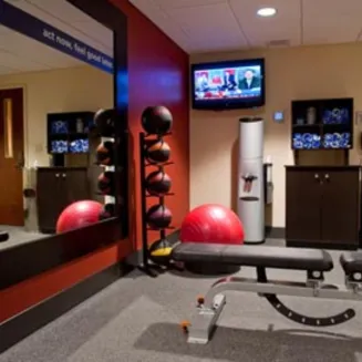 Hotel fitness room with exercise bench, medicine balls, and wall mirror.