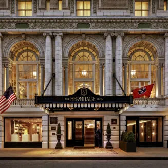 Exterior of The Hermitage Hotel with arched windows, flags, and grand entrance.