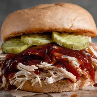 Smoked Pulled Chicken with BBQ Sauce & Pickles served on a Fresh Baked Bun.