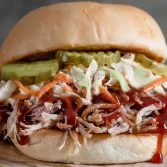 Smoked Pulled Pork with BBQ Sauce & Pickles served on a Fresh Baked Bun.