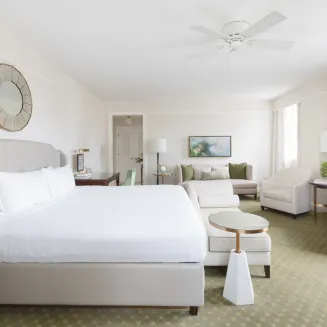 Spacious hotel suite with king bed, sitting area, and soft neutral tones.