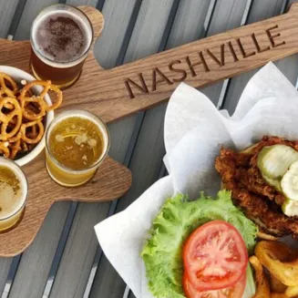 Nashville hot chicken sandwich with chips and beer flight served on a guitar-shaped tray.
