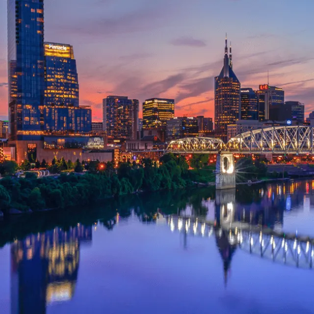 The Nashville skyline and Cumberland River lit up at dusk
