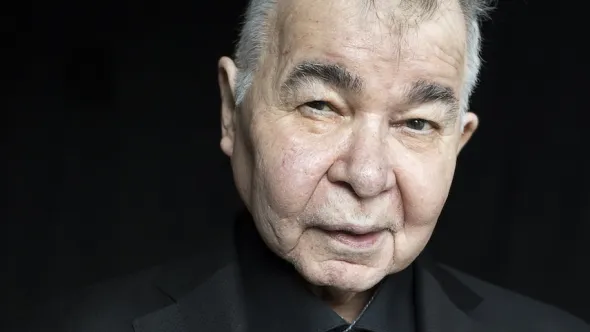 Portrait of John Prine in a black suit